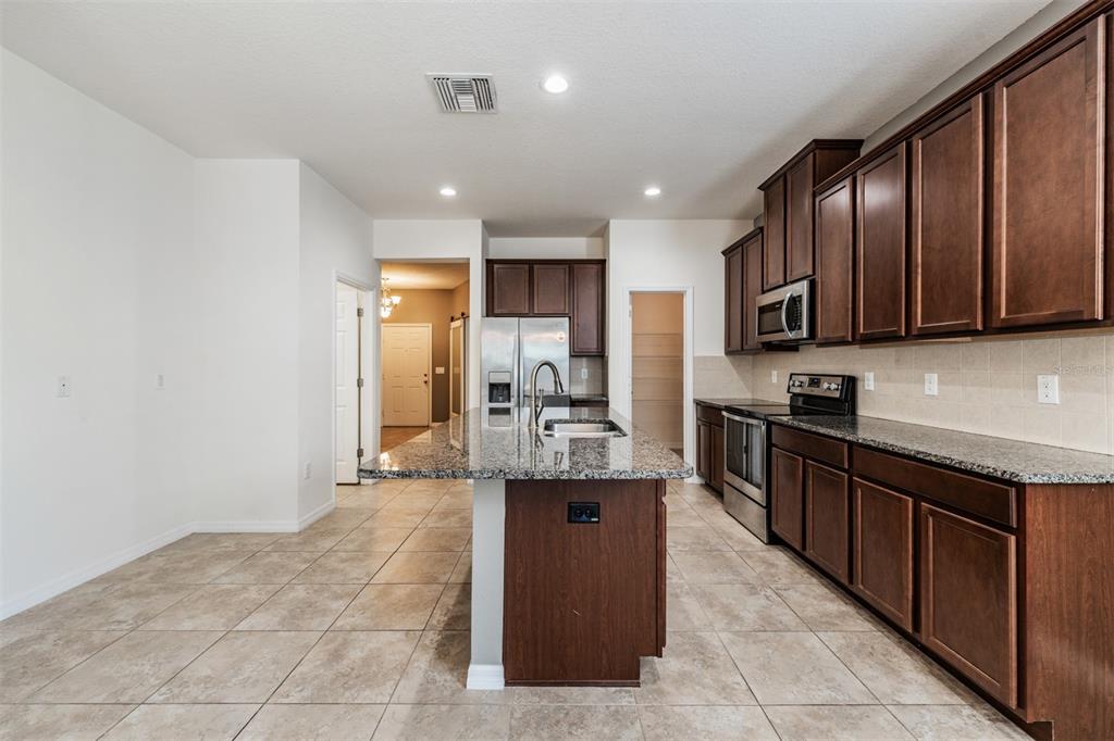 1570 Fox Grape Loop Lutz, FL 33558 - Photo 4 of 41 a large kitchen with stainless steel appliances granite countertop a stove refrigerator and a sink