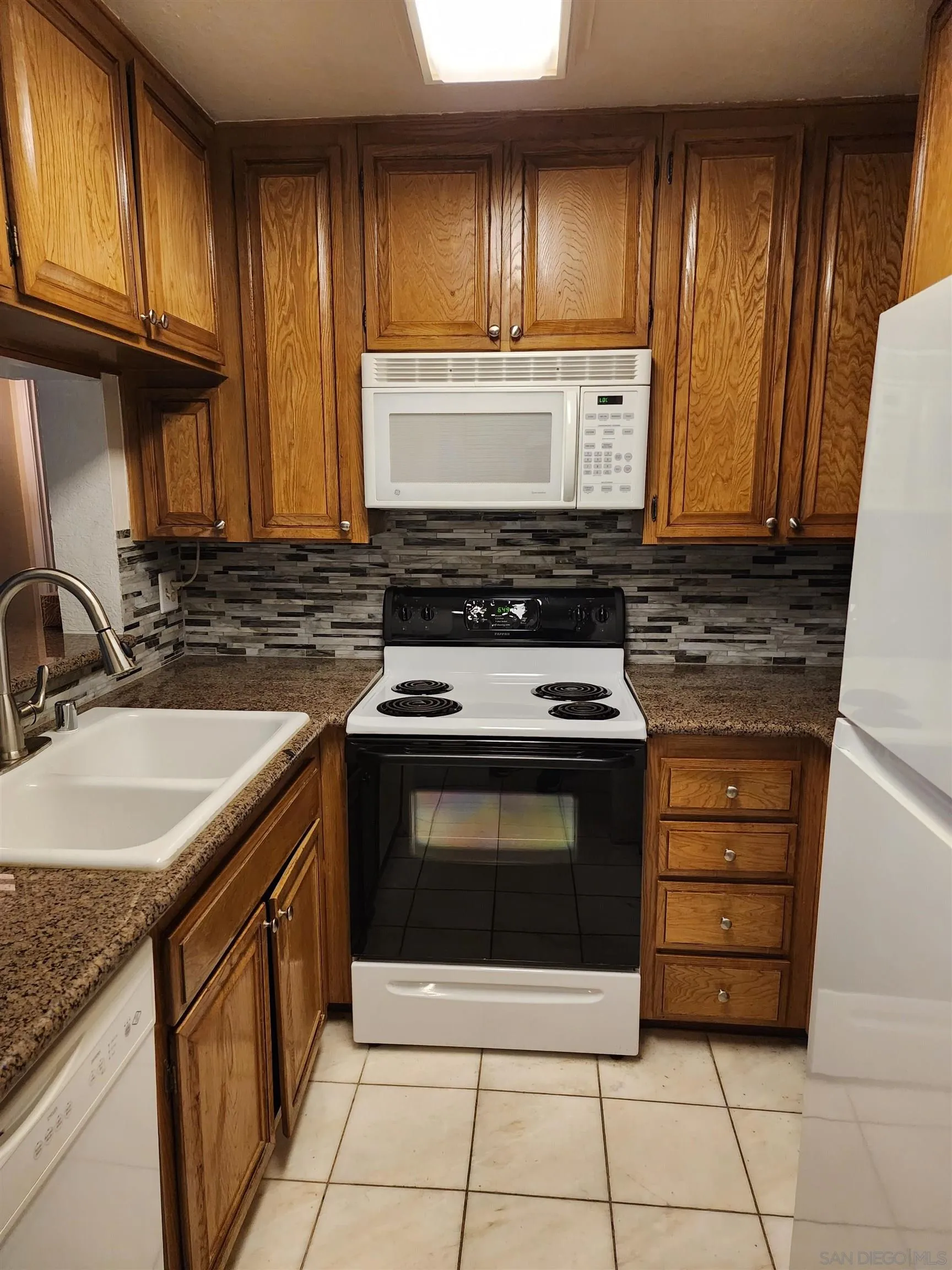 5705 Friars Road, Unit 22 San Diego, CA 92110 - Photo 4 of 38 a kitchen with granite countertop a stove sink and cabinets