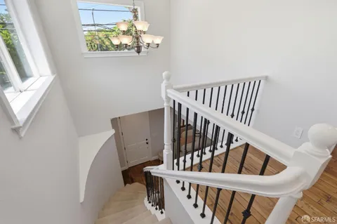 a view of staircase with railing and a chandelier