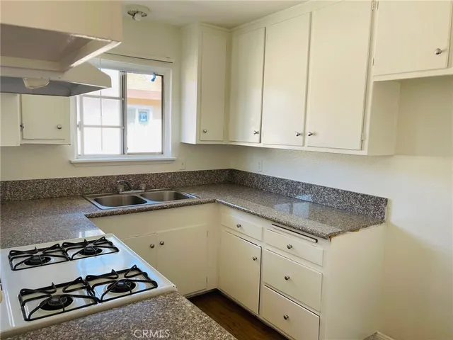 a kitchen with white cabinets stove and sink