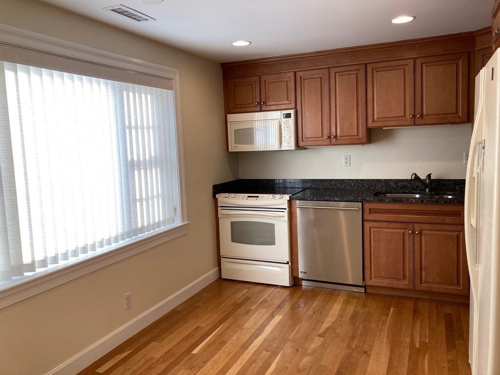 114 Jericho Road, Unit 114 Weston, MA 02493 - Photo 5 of 9 a kitchen with granite countertop white cabinets and white appliances