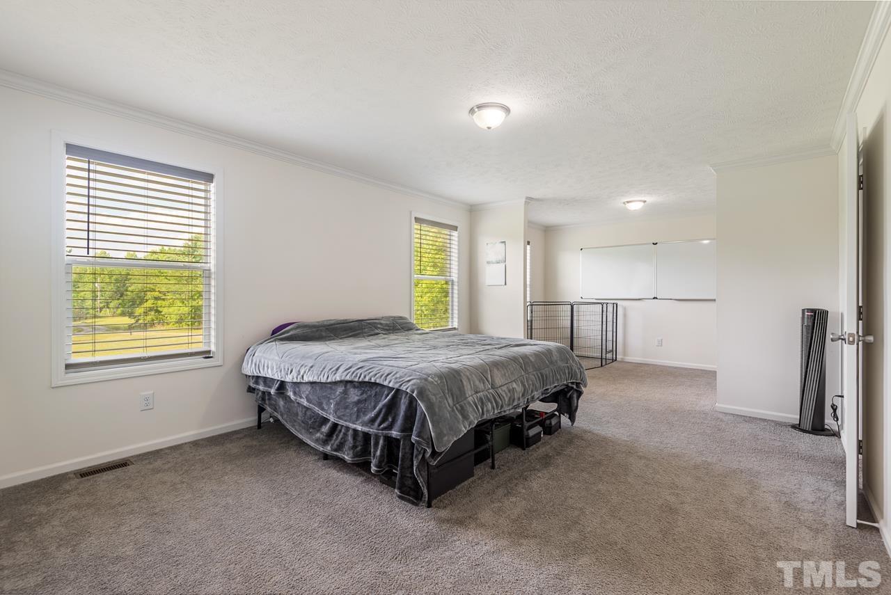 517 Circle B Farm Road Rougemont, NC 27572 - Photo 16 of 37 a spacious bedroom with a bed lamp and a large window
