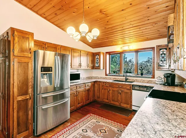 a kitchen with stainless steel appliances granite countertop a refrigerator and wooden cabinets