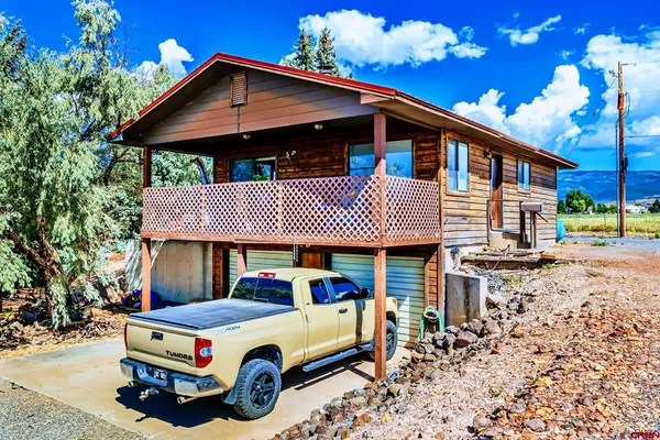 a blue and white house covered with tall trees