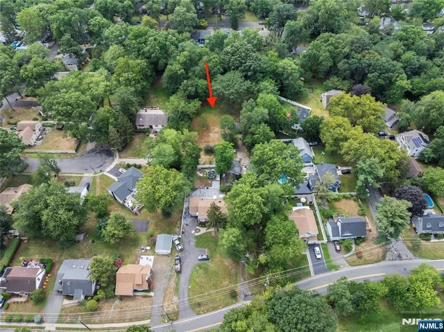 an aerial view of residential houses with outdoor space and trees all around