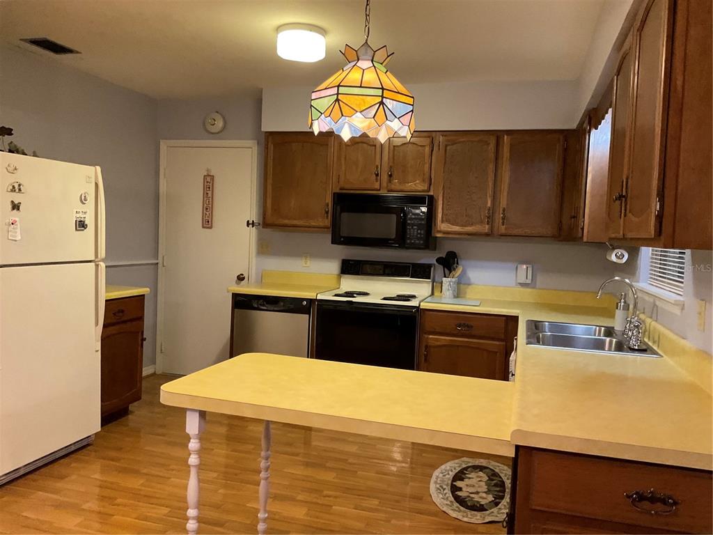 2438 Southeast 32nd Street Okeechobee, FL 34974 - Photo 10 of 42 a kitchen with a sink a refrigerator and a stove top oven