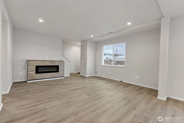 an empty room with wooden floor fireplace and window