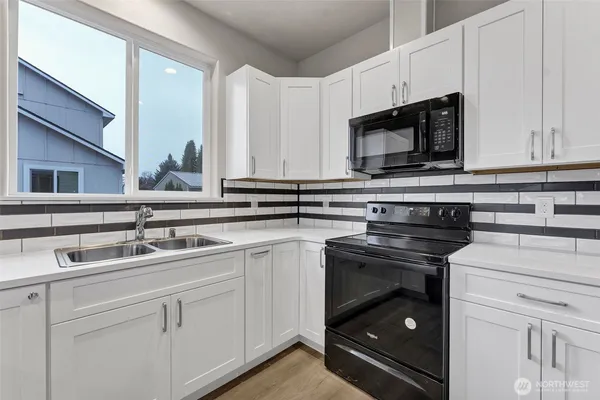 a kitchen with stainless steel appliances granite countertop white cabinets and a sink