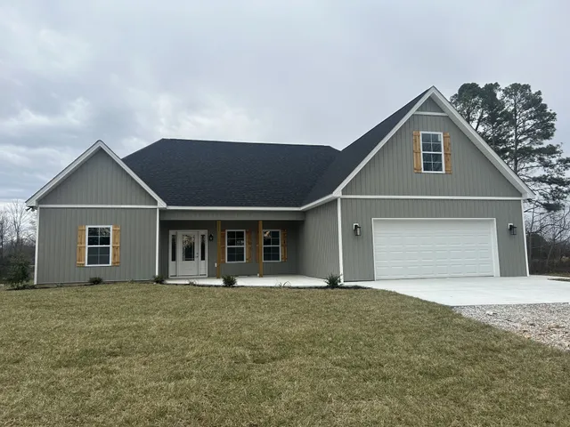a front view of house with yard and trees in the background