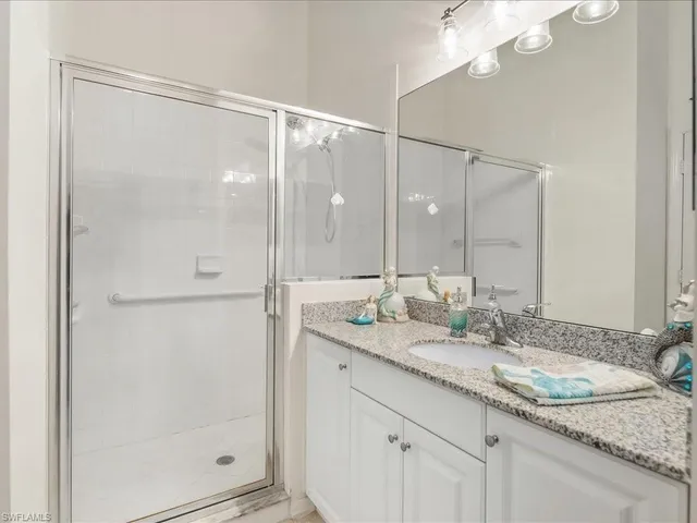 a bathroom with a granite countertop shower sink and mirror