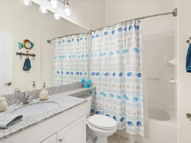 a bathroom with a granite countertop sink a toilet a mirror a shower curtain and a large mirror