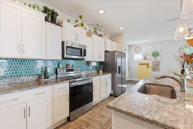 a kitchen with granite countertop a sink a stove a refrigerator and cabinets