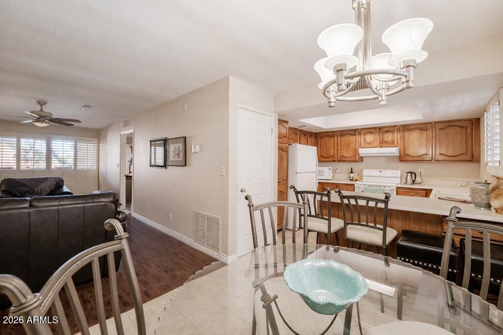 4303 East Cactus Road, Unit 403 Phoenix, AZ 85032 - Photo 10 of 37 a view of a dining room with furniture a kitchen and chandelier