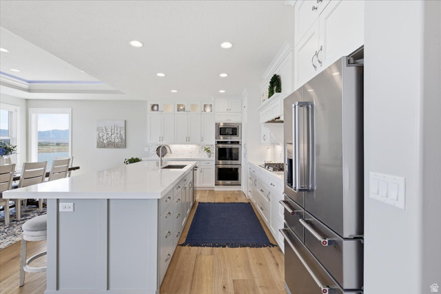 21 Pier Place Tooele, UT 84074 - Photo 18 of 112 Gourmet kitchen featuring a large central island with seating, stainless steel appliances, white cabinetry, wood-finish flooring, and recessed lighting