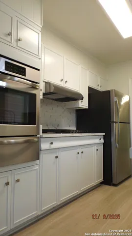 a kitchen with stainless steel appliances white cabinets and a refrigerator