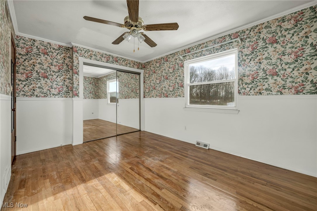 2514 Primewood Road Akron, OH 44305 - Photo 23 of 49 Unfurnished bedroom with wallpapered walls, multiple windows, a wainscoted wall, hardwood / wood-style floors, and a closet