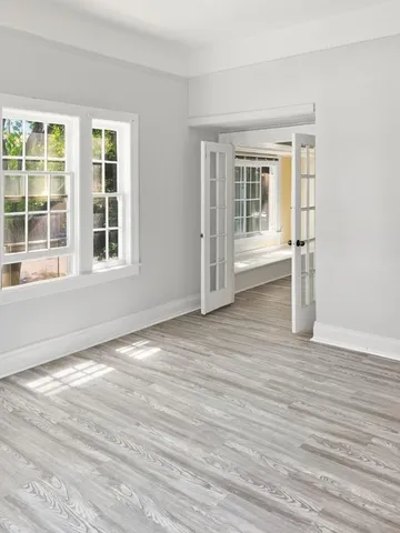 a view of an empty room with wooden floor and a window