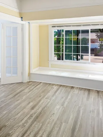 a view of a room with a large window and wooden floor