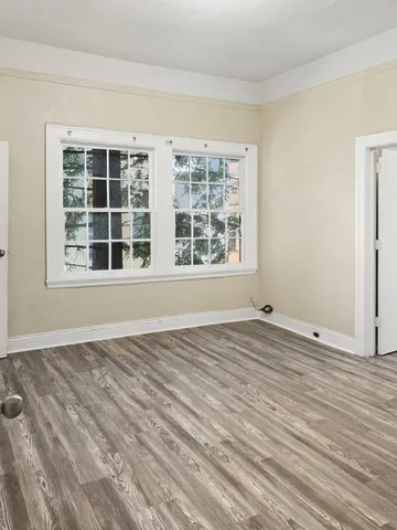 a view of an empty room with a window and wooden floor