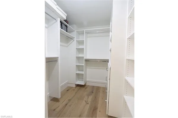 a view of walk in closet with clothes and shoes