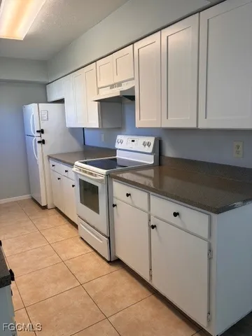 a kitchen with granite countertop white cabinets and white appliances