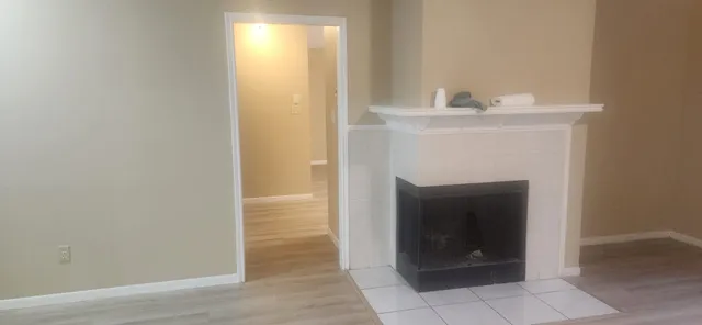 a view of an empty room with wooden floor and a fireplace