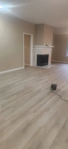 a view of empty room with wooden floor and fireplace