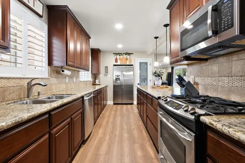 a large kitchen with stainless steel appliances granite countertop a stove sink and cabinets
