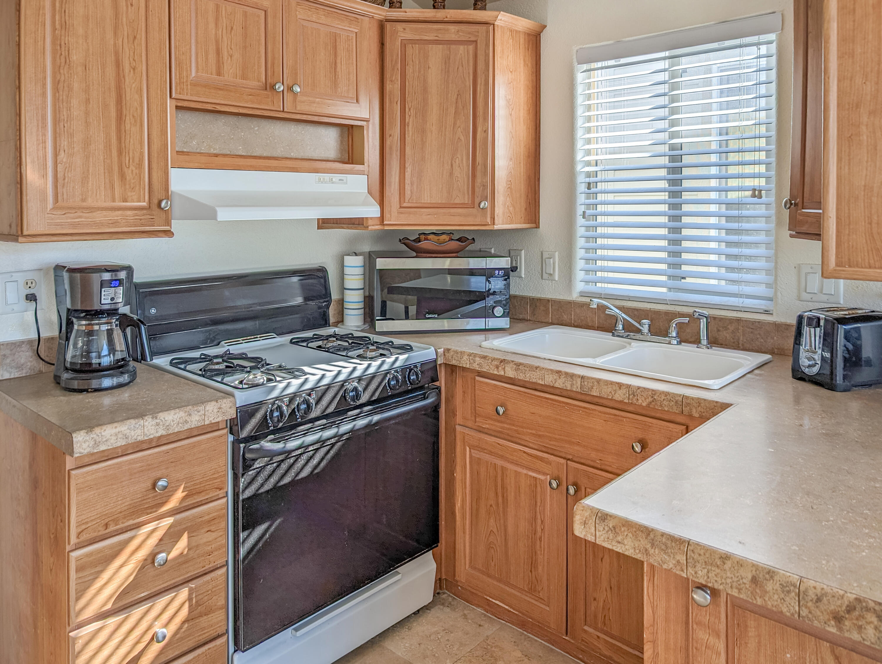 70200 Dillon Road, Unit 328 Desert Hot Springs, CA 92241 - Photo 13 of 25 a kitchen with granite countertop a sink a stove and cabinets