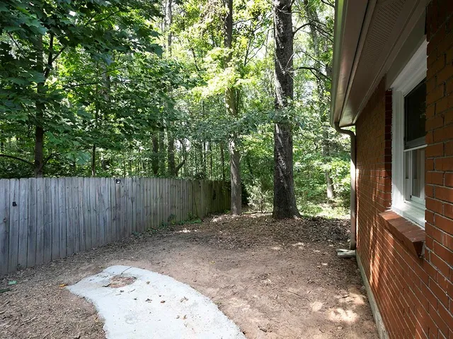a view of a backyard with large trees and wooden fence