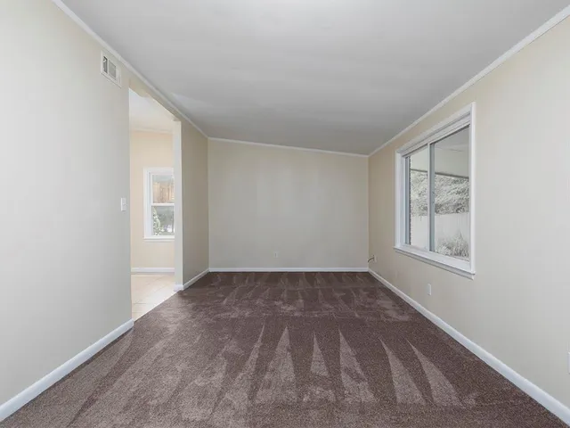 a view of an empty room with window and closet area