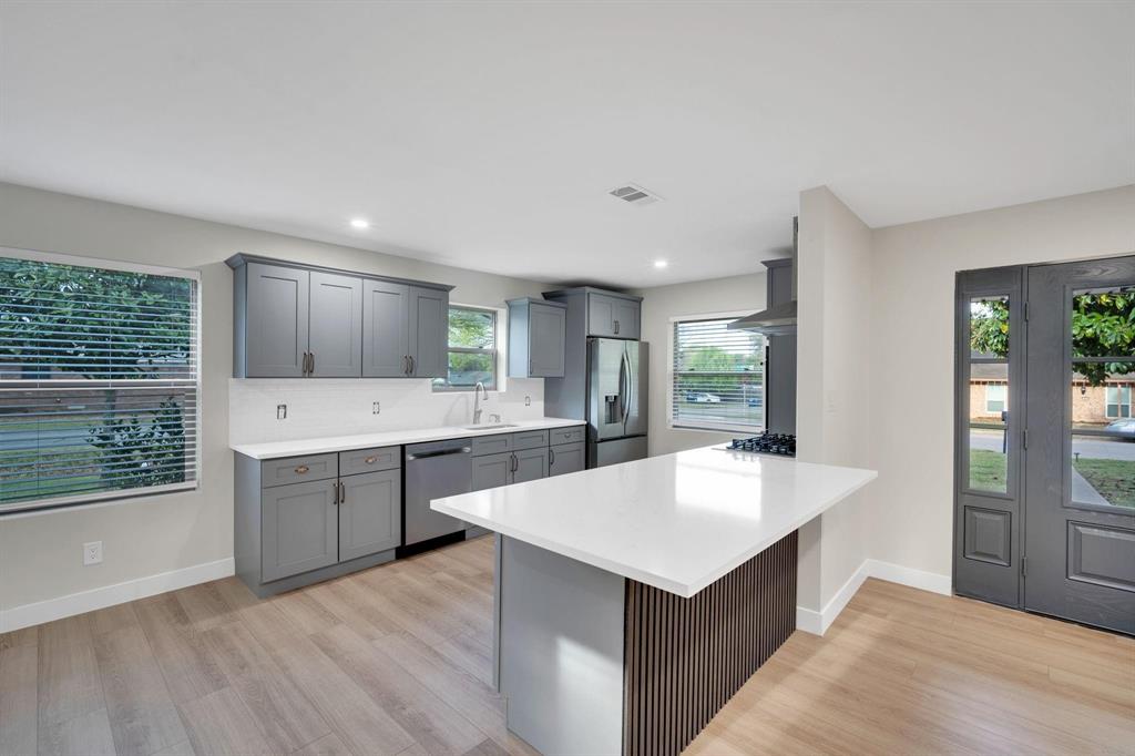 100 North Valley Street Red Oak, TX 75154 - Photo 4 of 31 a large kitchen with kitchen island a sink dishwasher a stove and a refrigerator with wooden floor