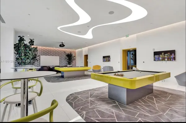 a living room with table pool table and a potted plant