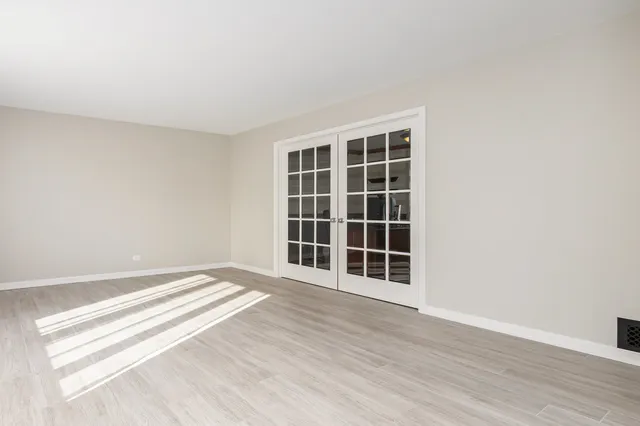 a view of an empty room with wooden floor and windows