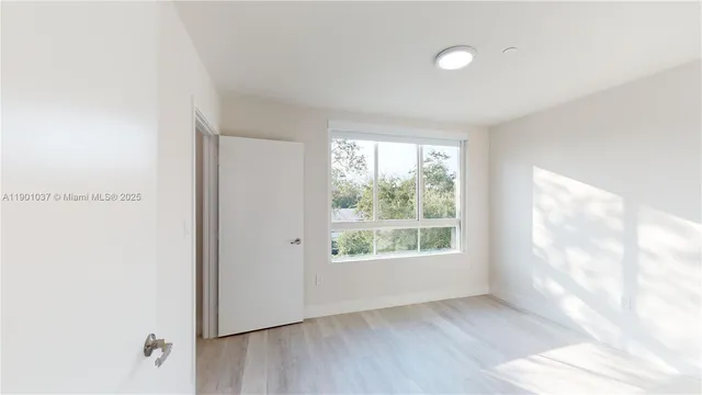 a view of a big room with wooden floor and windows