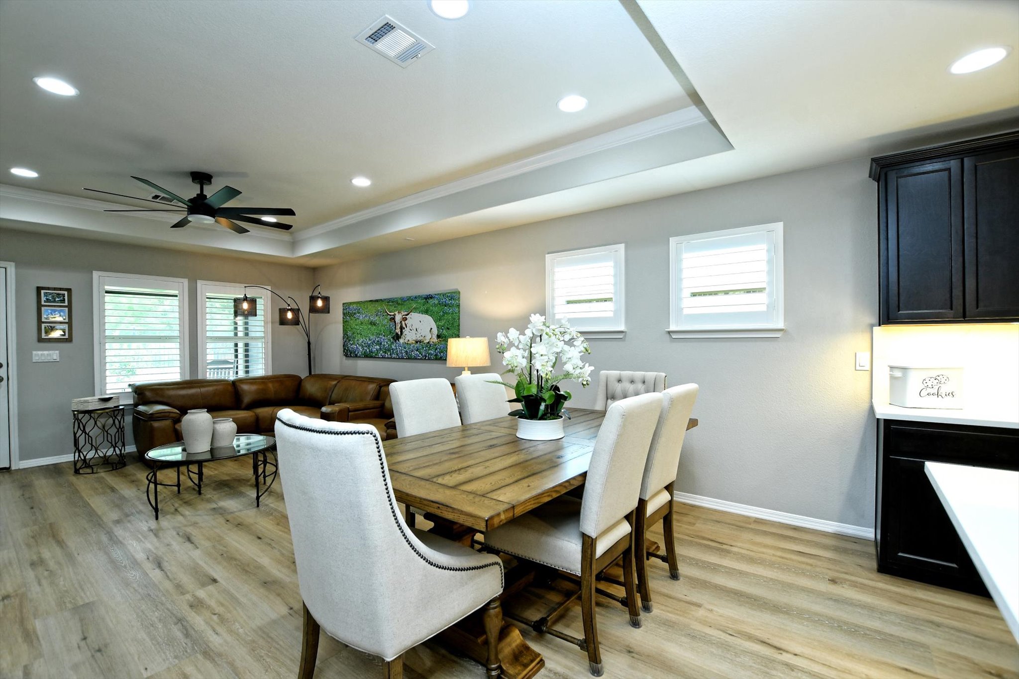 231 Hobby Street Georgetown, TX 78633 - Photo 7 of 29 An inviting open-concept space features warm wood-toned flooring and elegant tray ceilings with recessed lighting.