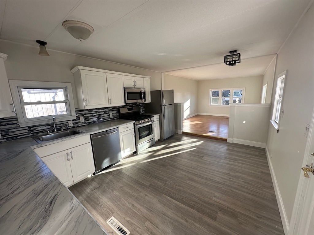 165 Newbury Street, Unit 2 Peabody, MA 01960 - Photo 6 of 8 a kitchen with stove cabinets and wooden floor