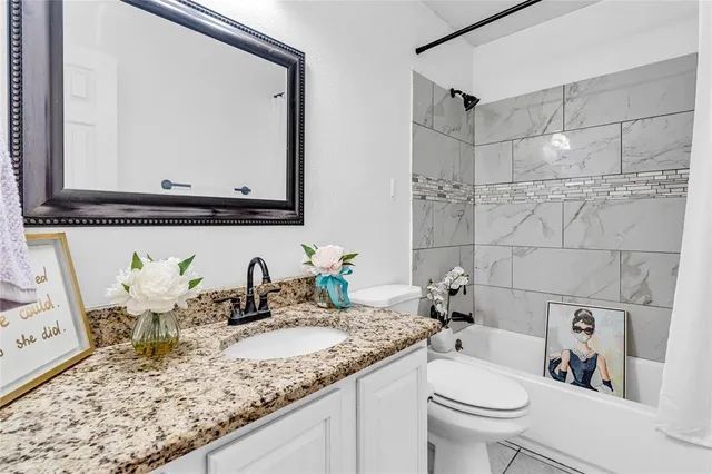 a bathroom with a granite countertop sink mirror vanity and toilet