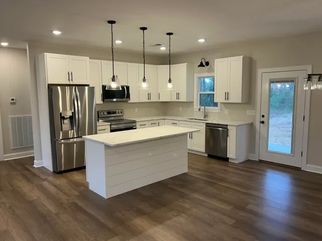 a kitchen with stainless steel appliances granite countertop a refrigerator a stove a sink and a oven