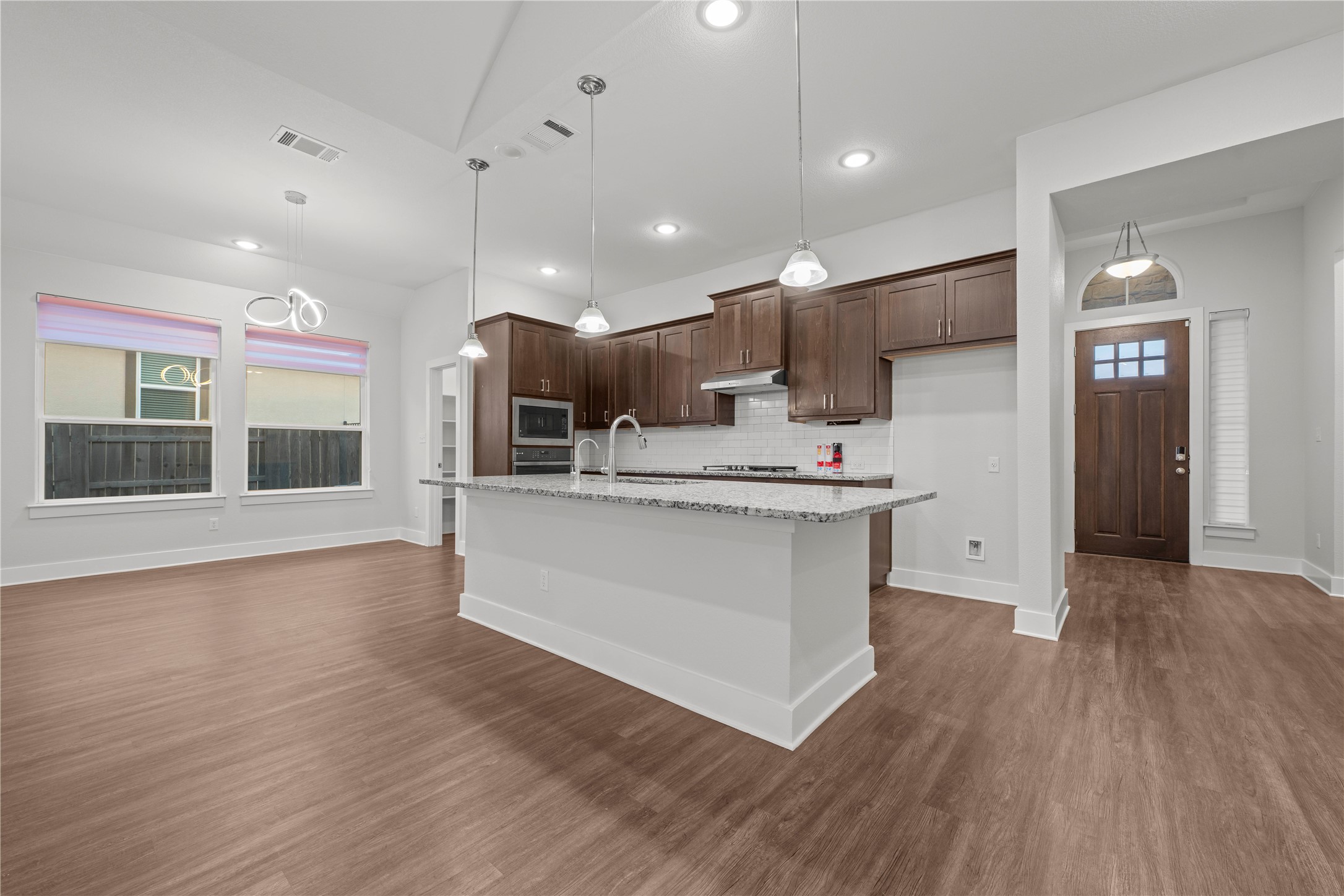 60 Rancho Trail Georgetown, TX 78628 - Photo 7 of 36 Warm wood flooring and an expansive kitchen island define this open-concept main living space.