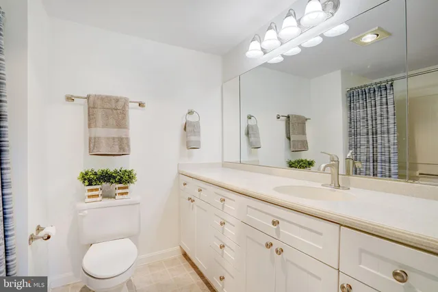 a bathroom with a granite countertop sink a large mirror and a toilet