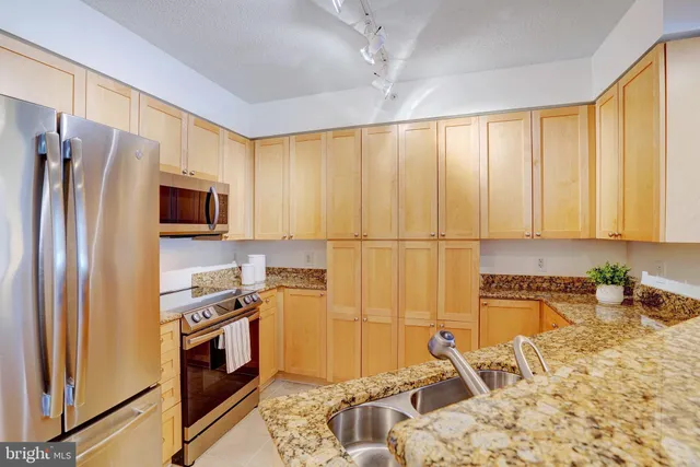 a kitchen with stainless steel appliances granite countertop a refrigerator sink and stove top oven