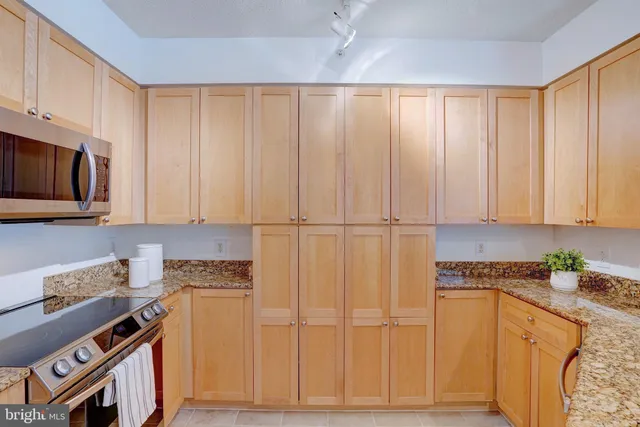 a kitchen with stainless steel appliances granite countertop a refrigerator a stove top oven with white cabinets and wooden floor