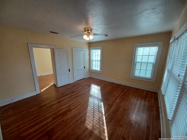 a view of empty room with wooden floor and fan