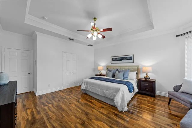 an empty room with wooden floor ceiling fan and windows