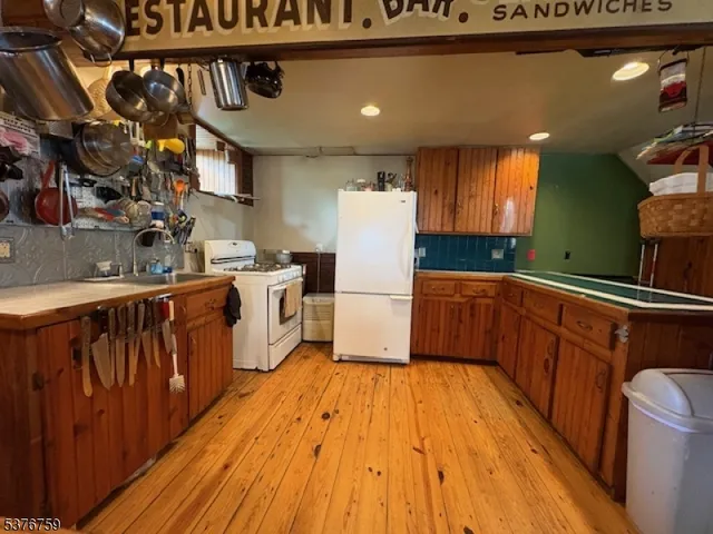 a kitchen with stainless steel appliances granite countertop a refrigerator a sink dishwasher a stove and white countertops with wooden floor