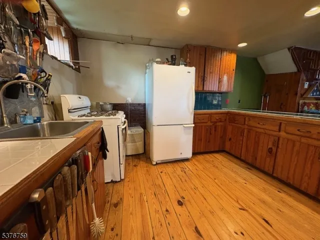 a kitchen with a refrigerator a stove and wooden floor