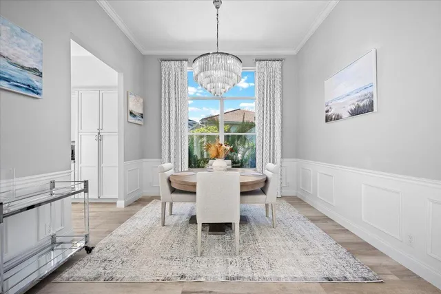 a dining room with wooden floor a chandelier a wooden table and chairs