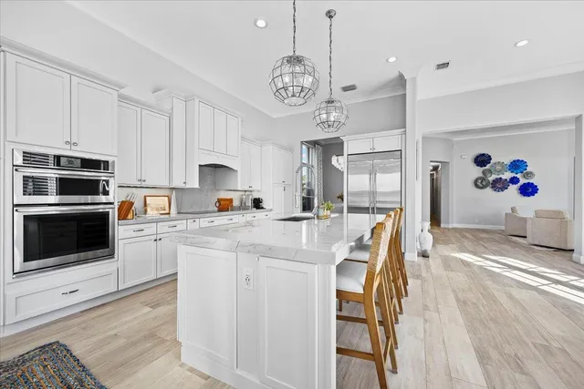 a large kitchen with kitchen island granite countertop a stove a sink a dining table and chairs with wooden floor