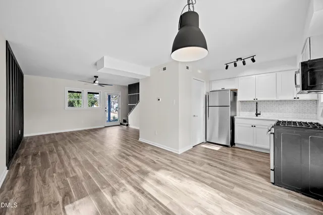 a view of kitchen and empty room with wooden floor